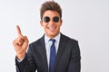 Young handsome businessman wearing suit and sunglasses over isolated white background with a big smile on face, pointing with hand Royalty Free Stock Photo