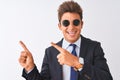 Young handsome businessman wearing suit and sunglasses over isolated white background smiling and looking at the camera pointing Royalty Free Stock Photo