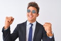 Young handsome businessman wearing suit and sunglasses over isolated white background very happy and excited doing winner gesture Royalty Free Stock Photo