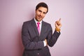 Young handsome businessman wearing suit and tie standing over isolated pink background with a big smile on face, pointing with Royalty Free Stock Photo