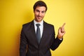 Young handsome businessman wearing suit and tie standing over isolated yellow background with a big smile on face, pointing with Royalty Free Stock Photo