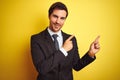 Young handsome businessman wearing suit and tie standing over isolated yellow background smiling and looking at the camera Royalty Free Stock Photo