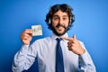 Young handsome call center agent man with beard working using headset holding help reminder very happy pointing with hand and Royalty Free Stock Photo