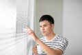 Young handsome carefree man near modern full length window enjoying a cup of coffee while looking outside, good morning Royalty Free Stock Photo