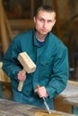 Young handsome carpenter works with a hammer and chisel