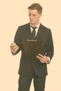 Young handsome Caucasian businessman holding clipboard while using mobile phone Royalty Free Stock Photo