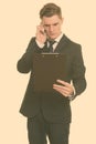 Young handsome Caucasian businessman talking on phone while reading clipboard Royalty Free Stock Photo