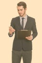 Young handsome Caucasian businessman using mobile phone while holding clipboard Royalty Free Stock Photo