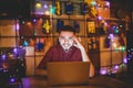 A young handsome Caucasian man with beard and toothy smile in a red checkered shirt is working behind a gray laptop sitting at a w Royalty Free Stock Photo