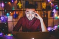 A young handsome Caucasian man with beard and toothy smile in a red checkered shirt is working behind a gray laptop sitting at a w Royalty Free Stock Photo