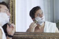 Young handsome caucasian man begins to shave with brush and foam, vintage style of old barber. Thoughtful serious look Royalty Free Stock Photo