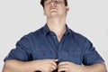 Young handsome caucasian man with dark curly hair and closed eyes unbuttons a blue jeans shirt. Hot sexy male. Royalty Free Stock Photo