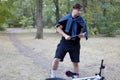 Young handsome caucasian man with dark hair holds the flashlight in abandoned park with very serious face expression. White bicycl Royalty Free Stock Photo