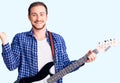 Young handsome caucasian man playing electric guitar celebrating victory with happy smile and winner expression with raised hands Royalty Free Stock Photo