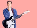 Young handsome caucasian man playing electric guitar covering mouth with hand, shocked and afraid for mistake Royalty Free Stock Photo