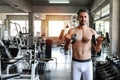 Young and handsome caucasian man in sportswear with mustache lifting a dumbbell in fitness gym with smiling face sport and Royalty Free Stock Photo