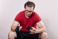 Young handsome caucasian man in sportswear, sitting, bandages hands with boxing bandage. Serious moment before or after match, or Royalty Free Stock Photo