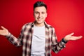 Young handsome caucasian man wearing casual modern shirt over red isolated background smiling showing both hands open palms, Royalty Free Stock Photo