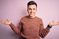 Young handsome caucasian man wearing casual winter sweater over pink isolated background smiling showing both hands open palms, Royalty Free Stock Photo