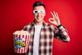 Young handsome caucasian man wearing 3d movie glasses and eating popcorn with a happy and cool smile on face Royalty Free Stock Photo