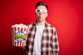 Young handsome caucasian man wearing 3d movie glasses and eating popcorn making fish face with lips, crazy and comical gesture Royalty Free Stock Photo