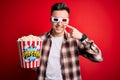 Young handsome caucasian man wearing 3d movie glasses and eating popcorn Pointing with hand finger to face and nose, smiling Royalty Free Stock Photo