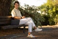 Young man sitting on bench at park, using laptop Royalty Free Stock Photo