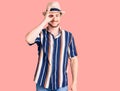 Young handsome caucasian man wearing summer hat doing ok gesture with hand smiling, eye looking through fingers with happy face Royalty Free Stock Photo