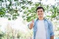 Young handsome caucasian, white smiling standing showing thumbs up in the park. Portrait of cheerful man toothy beaming smile Royalty Free Stock Photo