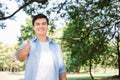 Young handsome caucasian, white smiling standing showing thumbs up in the park. Portrait of cheerful man toothy beaming smile Royalty Free Stock Photo