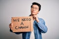 Young handsome chinese activist man protesting asking for change holding poster serious face thinking about question, very Royalty Free Stock Photo