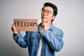 Young handsome chinese activist man protesting asking for freedom holding poster serious face thinking about question, very Royalty Free Stock Photo