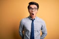 Young handsome chinese businessman wearing glasses and tie over yellow background afraid and shocked with surprise expression, Royalty Free Stock Photo