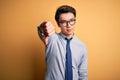 Young handsome chinese businessman wearing glasses and tie over yellow background looking unhappy and angry showing rejection and Royalty Free Stock Photo