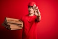 Young handsome chinese delivery man holding deliver boxes with Italian pizza with open hand doing stop sign with serious and Royalty Free Stock Photo
