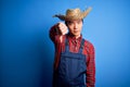 Young handsome chinese farmer man wearing apron and straw hat over blue background looking unhappy and angry showing rejection and Royalty Free Stock Photo