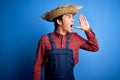 Young handsome chinese farmer man wearing apron and straw hat over blue background shouting and screaming loud to side with hand Royalty Free Stock Photo