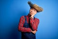 Young handsome chinese farmer man wearing apron and straw hat over blue background thinking looking tired and bored with Royalty Free Stock Photo
