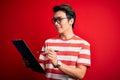 Young handsome chinese inspector man wearing glasses holding clipboard checklist with a happy face standing and smiling with a