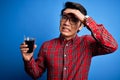 Young handsome chinese man drinking glass of coffee over isolated blue background stressed with hand on head, shocked with shame Royalty Free Stock Photo