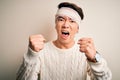 Young handsome chinese man injured for accident wearing bandage and strips on head angry and mad raising fists frustrated and
