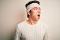 Young handsome chinese man injured for accident wearing bandage and strips on head angry and mad screaming frustrated and furious,