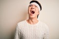 Young handsome chinese man injured for accident wearing bandage and strips on head angry and mad screaming frustrated and furious,