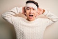 Young handsome chinese man injured for accident wearing bandage and strips on head Crazy and scared with hands on head, afraid and Royalty Free Stock Photo