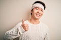Young handsome chinese man injured for accident wearing bandage and strips on head doing happy thumbs up gesture with hand