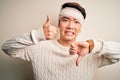 Young handsome chinese man injured for accident wearing bandage and strips on head Doing thumbs up and down, disagreement and