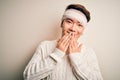 Young handsome chinese man injured for accident wearing bandage and strips on head laughing and embarrassed giggle covering mouth