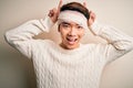 Young handsome chinese man injured for accident wearing bandage and strips on head Posing funny and crazy with fingers on head as