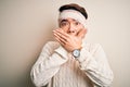 Young handsome chinese man injured for accident wearing bandage and strips on head shocked covering mouth with hands for mistake Royalty Free Stock Photo