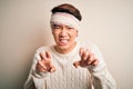 Young handsome chinese man injured for accident wearing bandage and strips on head smiling funny doing claw gesture as cat,